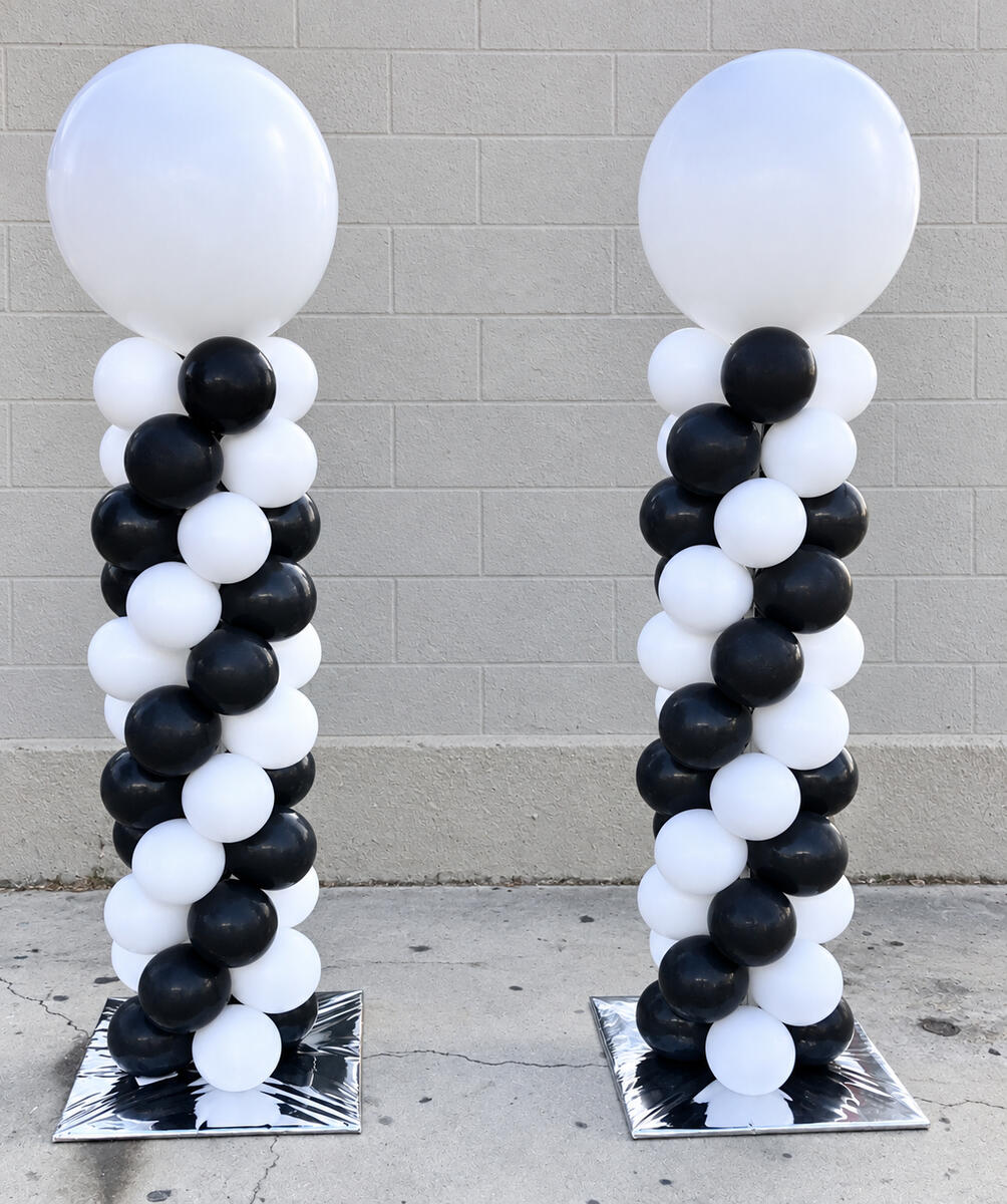 Two spiral black-and-white balloon columns with large white balloons on top.