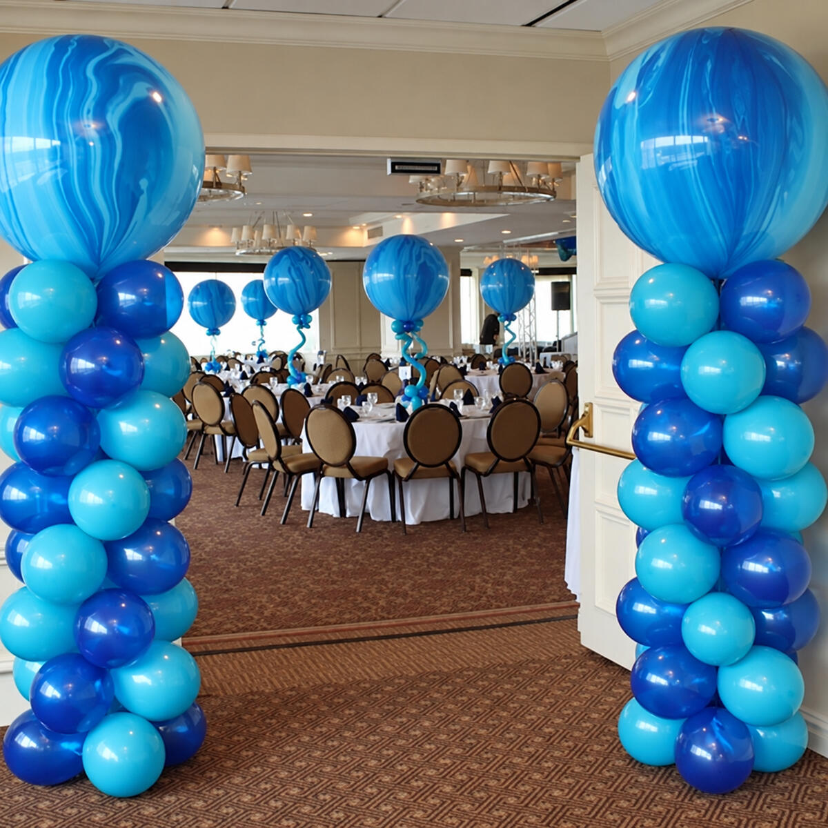 Blue and turquoise balloon columns with matching balloon displays on banquet tables.