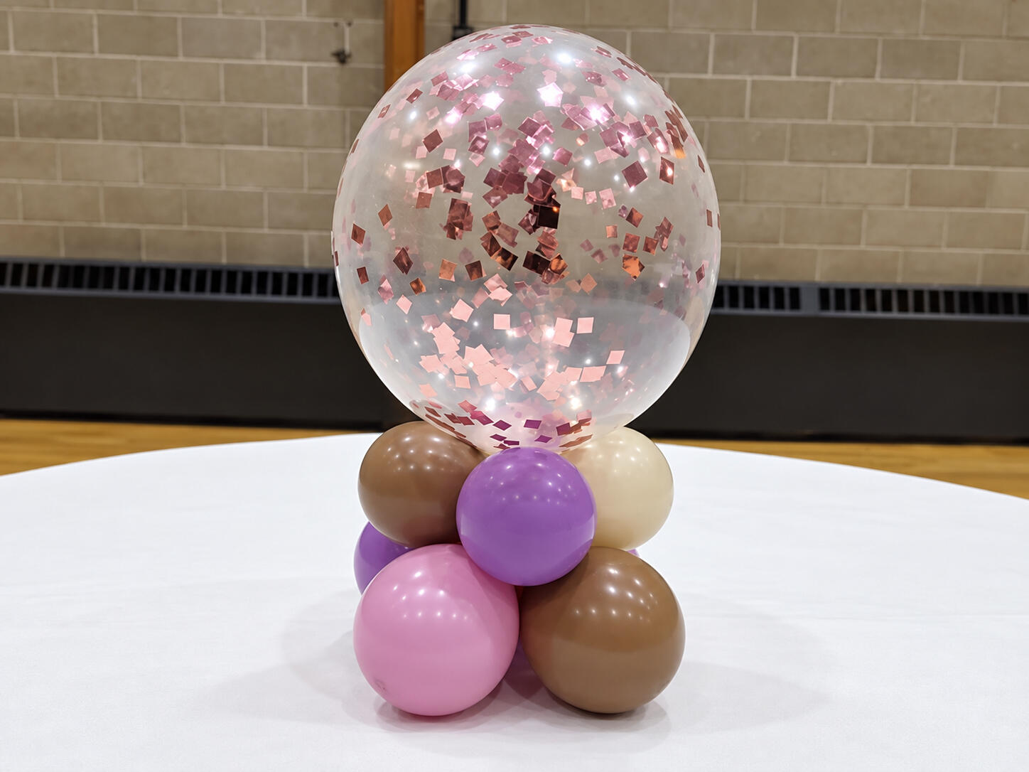Clear confetti balloon above a small pink, purple, cream and brown balloon base.
